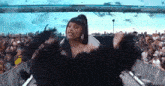 a woman in a black dress is dancing on a stage in front of a crowd of people .