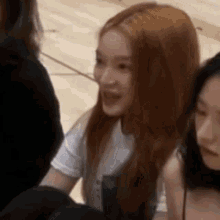 a group of women are sitting next to each other on a wooden floor and talking to each other .