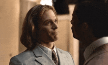 two men are looking at each other and one is wearing a suit