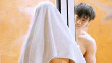 a shirtless man is standing in front of a mirror with a white cloth covering his head .