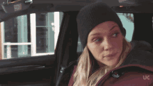 a woman wearing a beanie and a jacket with uc on it