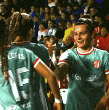 a woman in a green herbalife shirt shakes hands with another woman in a green shirt