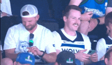a man in a timberwolves jersey is sitting in the stands