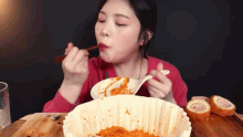 a woman is eating food with chopsticks from a bowl