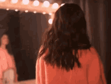 a woman is standing in front of a mirror in a dressing room .