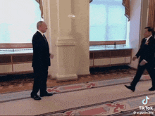 a man in a suit and tie is walking down a hallway