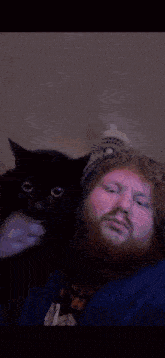 a man is laying on a bed with a cat on his chest