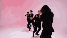 a group of people in black suits are dancing in front of a pink wall