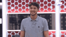 a man wearing a grey polo shirt is smiling in front of a wall with red polka dots