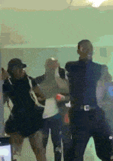 a group of people are dancing in a room with a green wall .