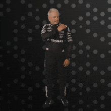 a man in a petronas outfit stands in front of a dark background