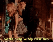a man is holding a woman in his arms while another man says gotta help wifey first bro .