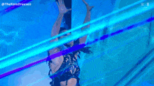 a woman in a black dress is dancing in front of a blue background with the letters n on the bottom