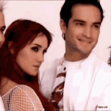 a man and a woman are standing next to each other and the woman is looking at the man .