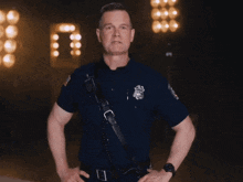 a police officer stands with his hands on his hips in front of lights