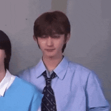 a man in a blue shirt and tie saluting while standing next to another man .