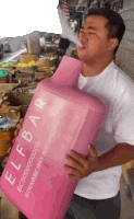 a man in a white shirt is holding a large pink container that says elfbar on it