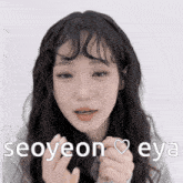 a girl with long hair is making a heart shape with her hands and the words seoyeon eya are above her
