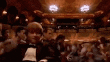 a man in a tuxedo is surrounded by a crowd of people .