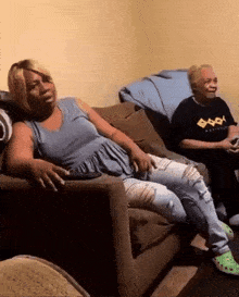 two women are sitting on a couch with one wearing a black shirt that says ' agility ' on it