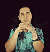 a man wearing a blue shirt with palm trees on it and a watch on his wrist