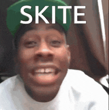 a man wearing a green hat and a white shirt with the word skite on it
