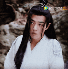 a man with long black hair is wearing a white shirt with chinese characters on the sleeves