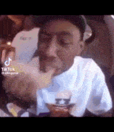 a man in a white shirt is eating a sandwich with his hand .