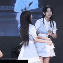 a girl in a blue dress holds a microphone while standing next to another girl