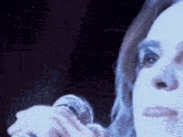 a woman singing into a microphone with a blue light behind her