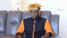 a man is sitting on a couch with a wig on his head .