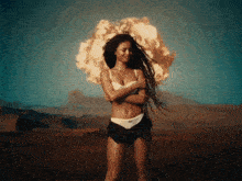 a woman in a white bra and black shorts is standing in front of an explosion