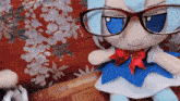 a stuffed doll with glasses and a red bow