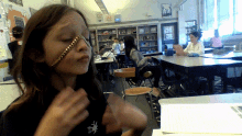 a girl with a chain around her face is in a classroom with other students