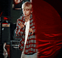 a man in a plaid shirt is standing in front of a red cloth