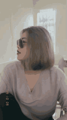a woman wearing sunglasses and a sweater has a picture of her taken on october 9th