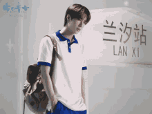 a man with a backpack standing in front of a sign that says lan xi