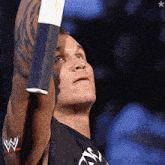 a man with a tattoo on his arm is wearing a black shirt with a w logo on it