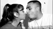 a black and white photo of a man and a woman kissing .