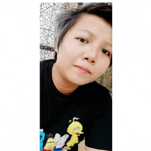a woman wearing a black shirt with sesame street characters on it is taking a selfie .