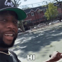 a man wearing a hat says hi in front of a building