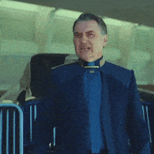 a man in a blue suit and tie is standing next to a railing .