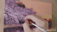 a person is painting a cherry blossom tree on a piece of paper