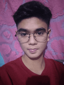 a young man wearing glasses and a red shirt is taking a selfie