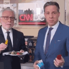 two men are standing next to each other in front of a cnn dc sign .