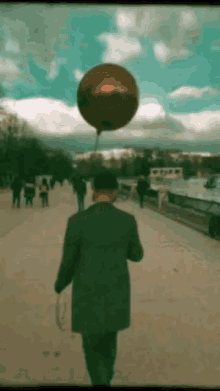 a man in a suit is walking with a red balloon hanging from his arm