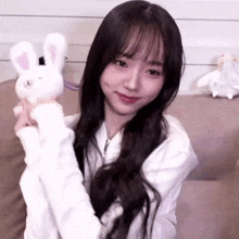 a young woman is holding a stuffed rabbit in her hands and smiling .