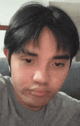 a close up of a man 's face with a grey shirt on