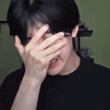 a person is covering their face with their hands .