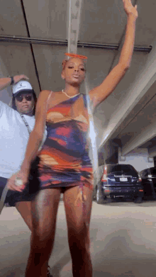 a woman in a dress is dancing in a parking garage with a man behind her